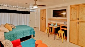 Un dormitorio con cama, escritorio, silla, televisor y armarios de madera.