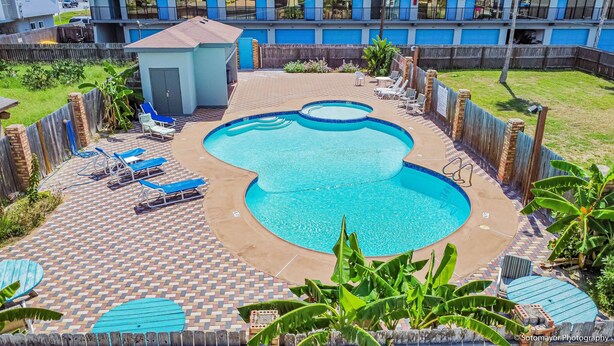 Una piscina con varias secciones, rodeada de sillones de descanso y una pequeña casa para la piscina.