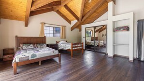 A spacious bedroom with wooden beams, a large bed, a smaller bed, and a wardrobe. - A Resort like Destination & Sleeps 16 Comfortably  (Big Bear Lake)