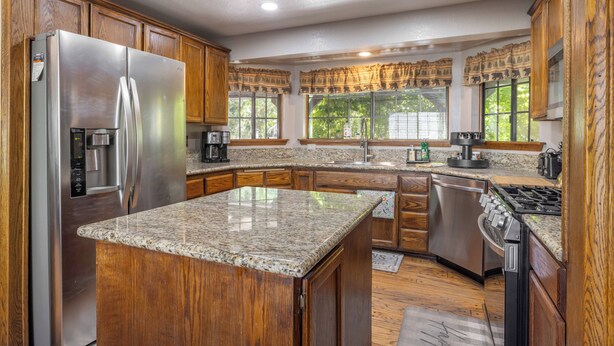 A kitchen with granite countertops, wooden cabinets, stainless steel appliances, and large windows with decorative valances. - A Resort like Destination & Sleeps 16 Comfortably  (Big Bear Lake)