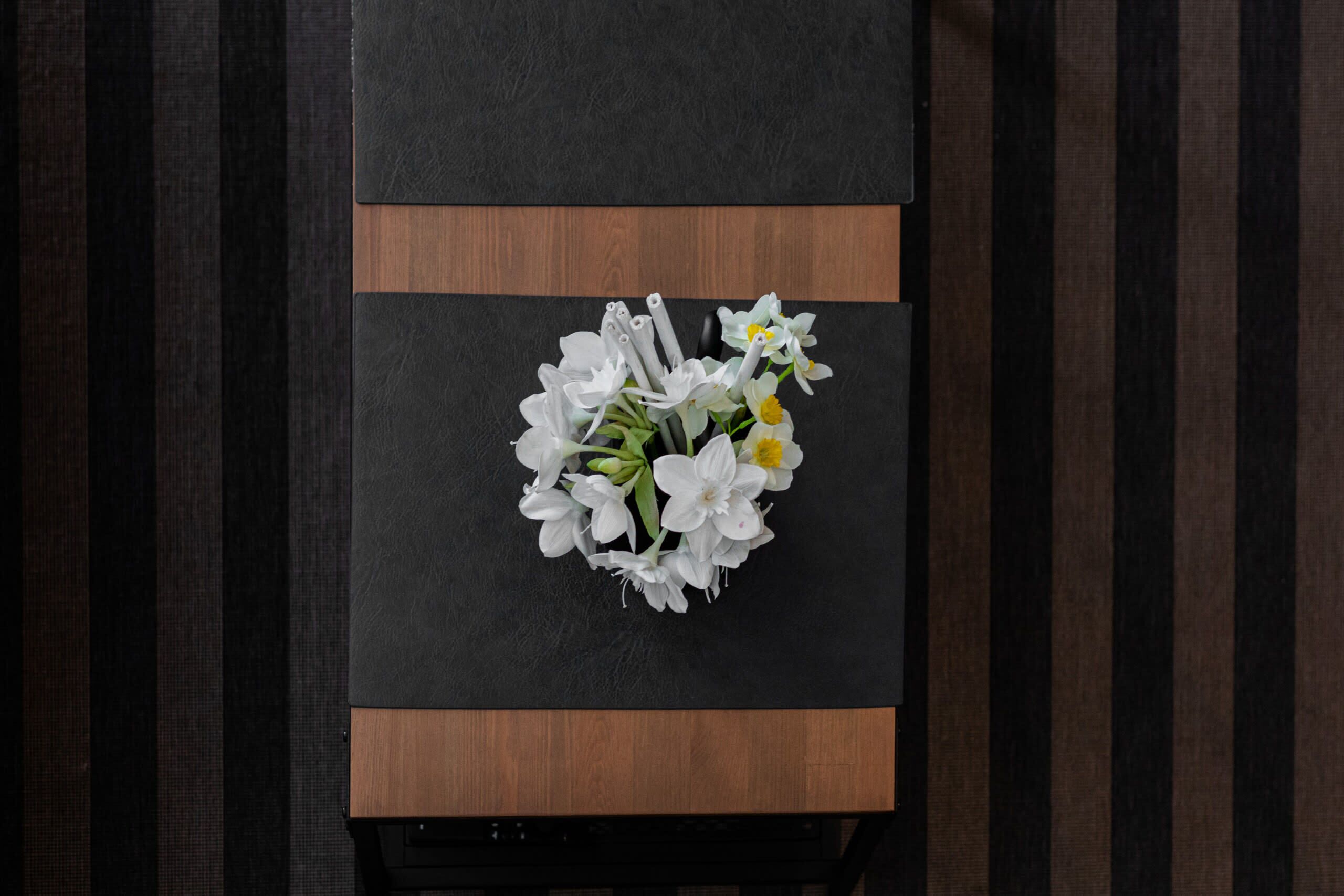 A table with a black and brown design, topped with a bouquet of white flowers.