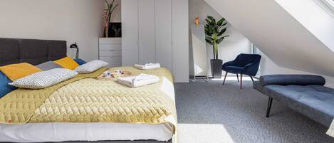 Un dormitorio moderno con una cama, un banco, una silla, un armario y un tragaluz.