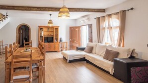 Un salon chaleureux avec une table à manger en bois, un canapé et un meuble pour la télévision.
