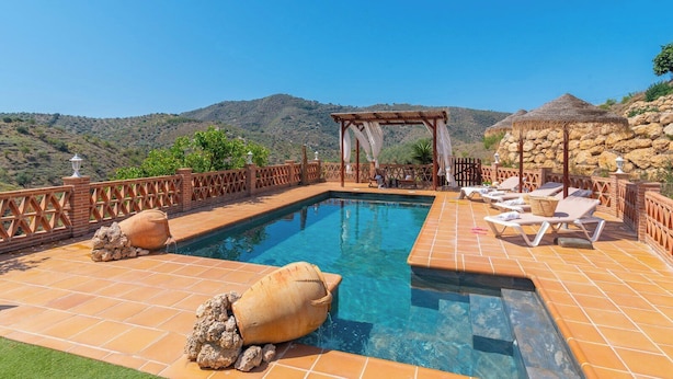Une piscine dotée d’une pergola, de chaises longues et offrant une vue sur les montagnes.