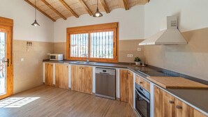 Une cuisine avec des meubles en bois, un lave-vaisselle en acier inoxydable et une fenêtre avec des barreaux.