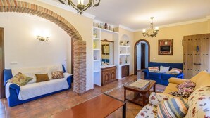 Una sala de estar con dos sofás, una mesa de centro y una chimenea de ladrillo. Hay estantes con objetos decorativos y un espejo en la pared.