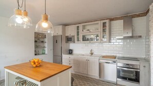 A modern kitchen with white cabinets, stainless steel appliances, and a wooden island. - Casa Trigueros Alozaina by Ruralidays (Málaga)