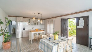 A kitchen with white cabinets, a wooden island, and a dining area with a table set for two. - Casa Trigueros Alozaina by Ruralidays (Málaga)