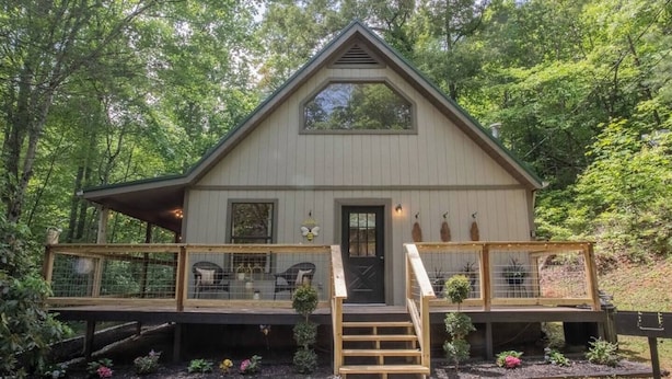 A wooden cabin with a front porch, a covered deck, and a small staircase leading to the entrance. - BEES KNEES A-frame Cabin for 2 * hot tub wifi (Gatlinburg)
