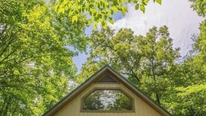 A two-story cabin with a gabled roof, a front porch with a railing, and a small deck area. - BEES KNEES A-frame Cabin for 2 * hot tub wifi (Gatlinburg)