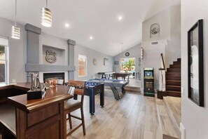 A spacious living area with a pool table, foosball table, and a bar area.