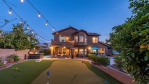 A two-story house with a front lawn, a patio, and string lights.