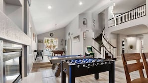 A spacious indoor area with a foosball table, a fireplace, and a staircase.