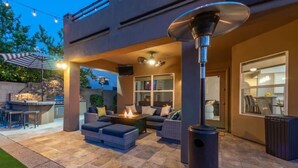 An outdoor patio with a fire pit, seating, and a modern outdoor kitchen.