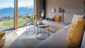 Una sala de estar moderna con un ventanal grande, una chimenea y un sofá con cojines.
