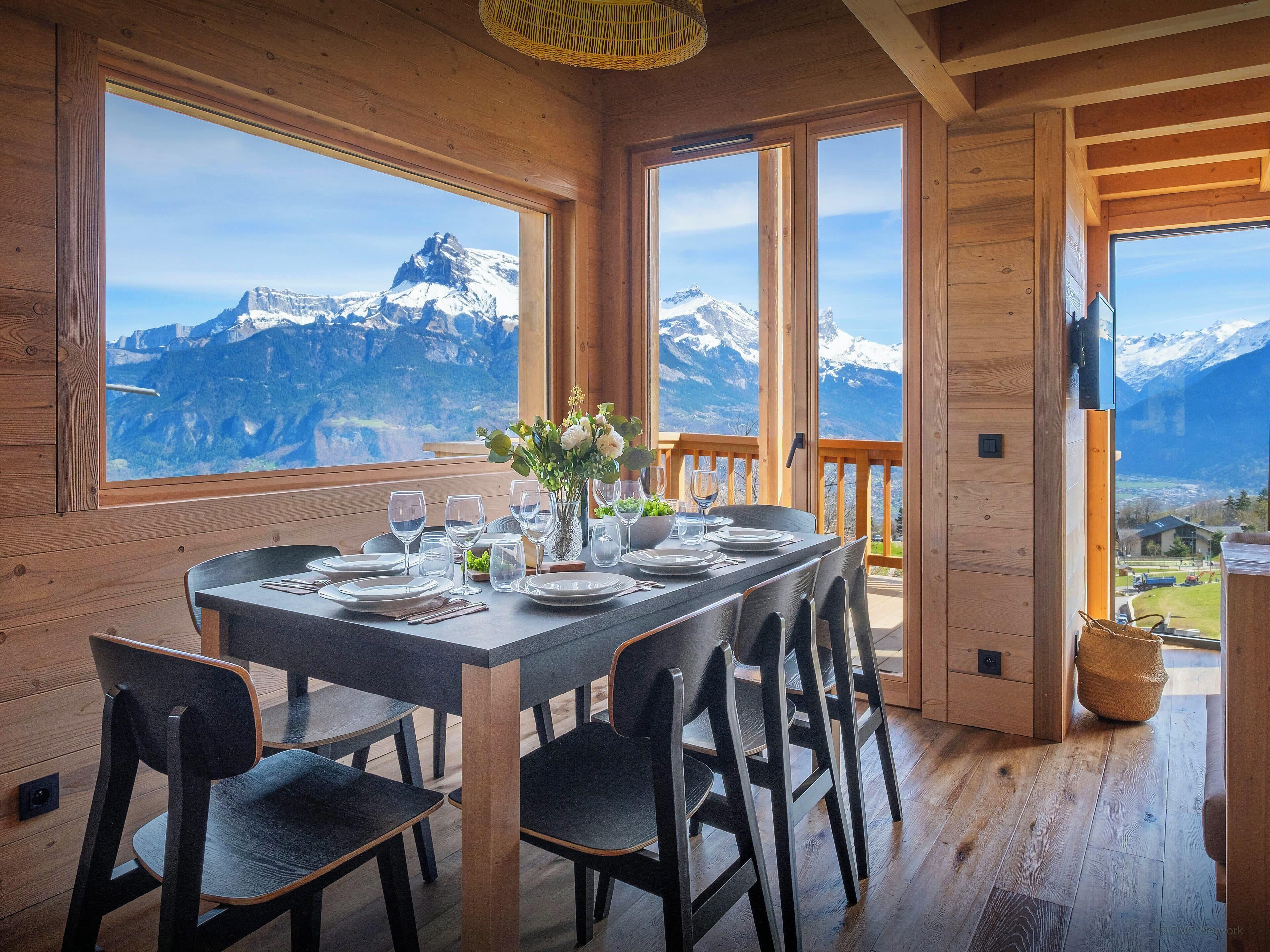 Comedor con mesa para seis, amplias ventanas con vista a la montaña y detalles de madera.