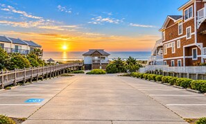 A beachfront parking lot with a view of the ocean and sunset.