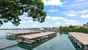 Een jachthaven met verschillende boten afgemeerd, een houten steiger en gebouwen en groen op de achtergrond.