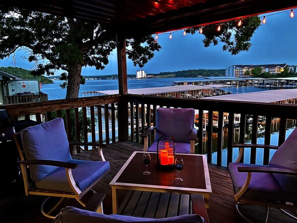 Relax with a view of the water and distant buildings from this outdoor seating area, featuring a table and two chairs.