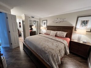 A bedroom with a large bed, two bedside tables with lamps, a wooden headboard, and a wall-mounted fish decoration. - Direct Oceanfront Condo w/ Balcony - King Bed - Pool - Hot Tub - Myrtle Beach (Myrtle Beach)