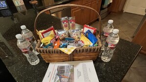 A kitchen counter with a basket of snacks, bottled water, and a welcome brochure. - Unwind and Relax at Hidden Trails Retreat (Payson)