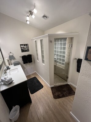 A modern bathroom with a white sink, black towel, and a glass shower enclosure. - Unwind and Relax at Hidden Trails Retreat (Payson)