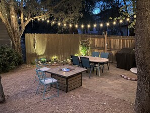 An outdoor patio with a wooden table and chairs, surrounded by a wooden fence and string lights. - Unwind and Relax at Hidden Trails Retreat (Payson)