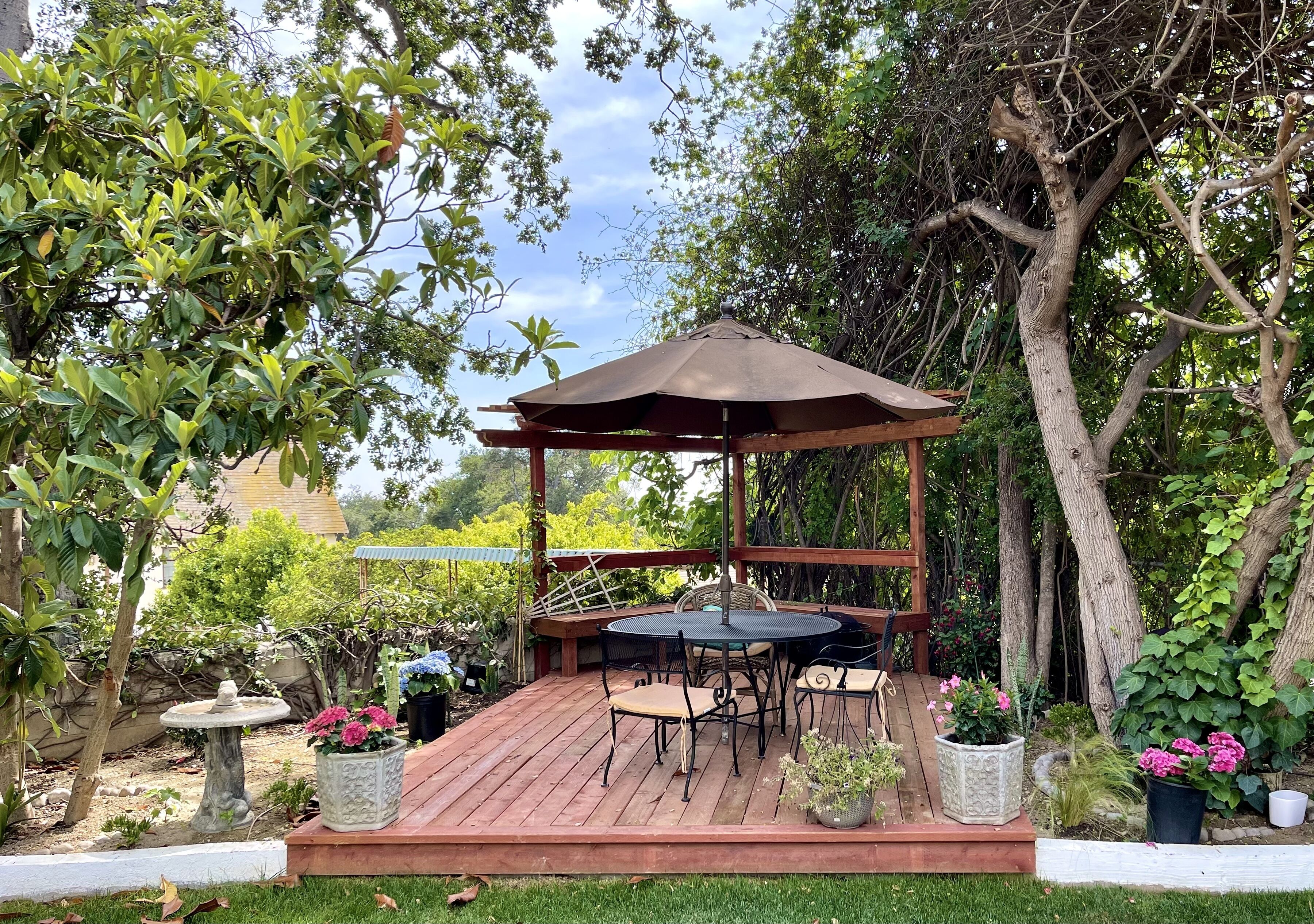 A wooden deck with a gazebo, a round table, and chairs.