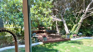 Vista de un jardín con un patio, una mesa y sillas.