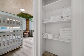 A room with a bunk bed, a white closet with neatly folded towels, and a wooden tree trunk decoration. - Room for the whole family 1/2 hour to Mohegan and Mystic Seaport (Colchester)
