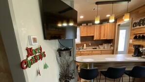 Una cocina moderna con armarios de madera, un televisor de pantalla plana y una barra con taburetes.