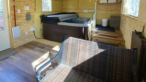 Una habitación con ventilador de techo, cama, silla y una mesita.