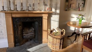 A fireplace with a mantel decorated with candles and a basket of firewood. - Six on Castle (Tiverton)