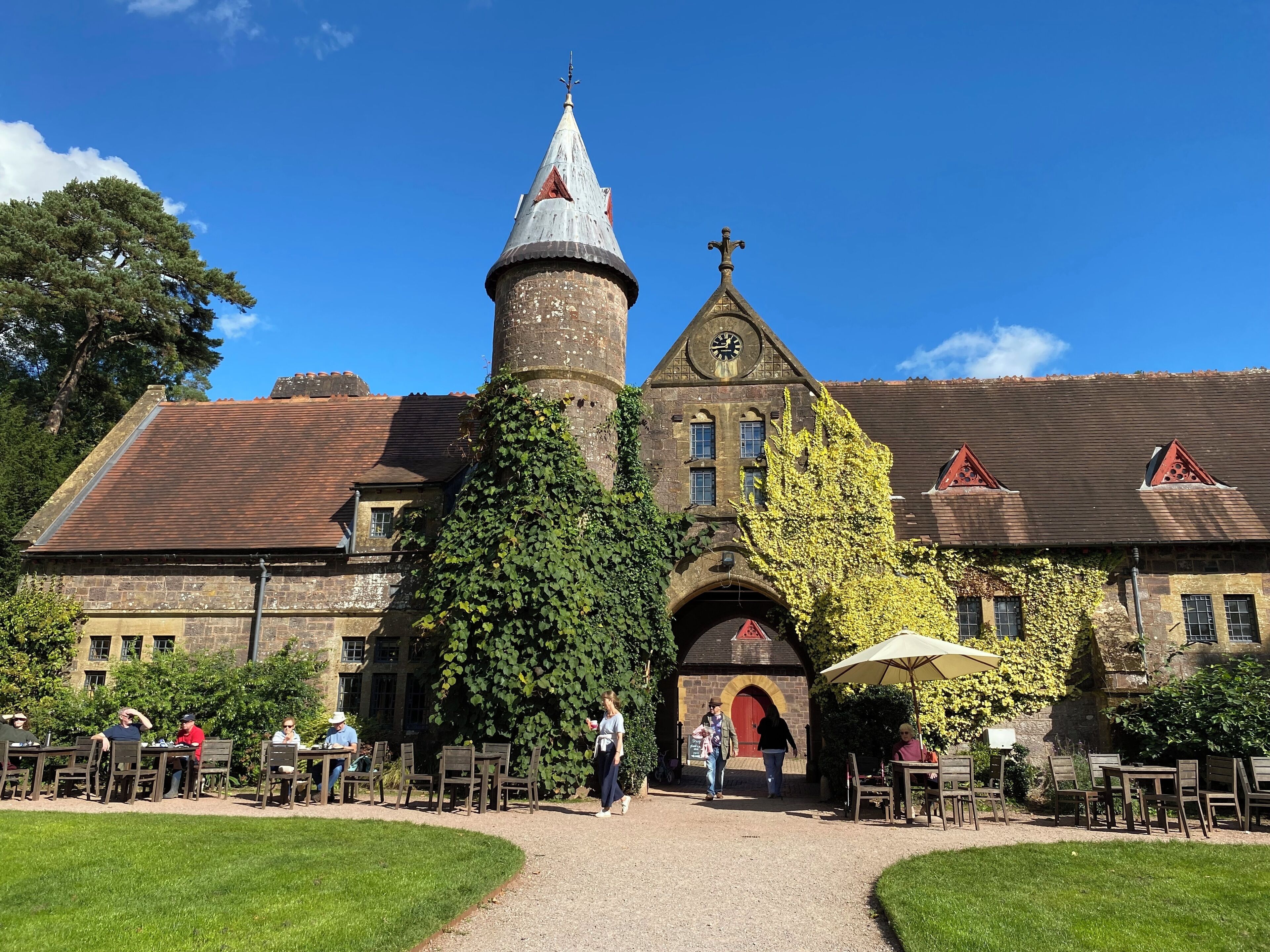 A historic building with a prominent tower, ivy-covered walls, and a red door.