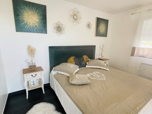 A bedroom with a large bed, a nightstand, and wall art.