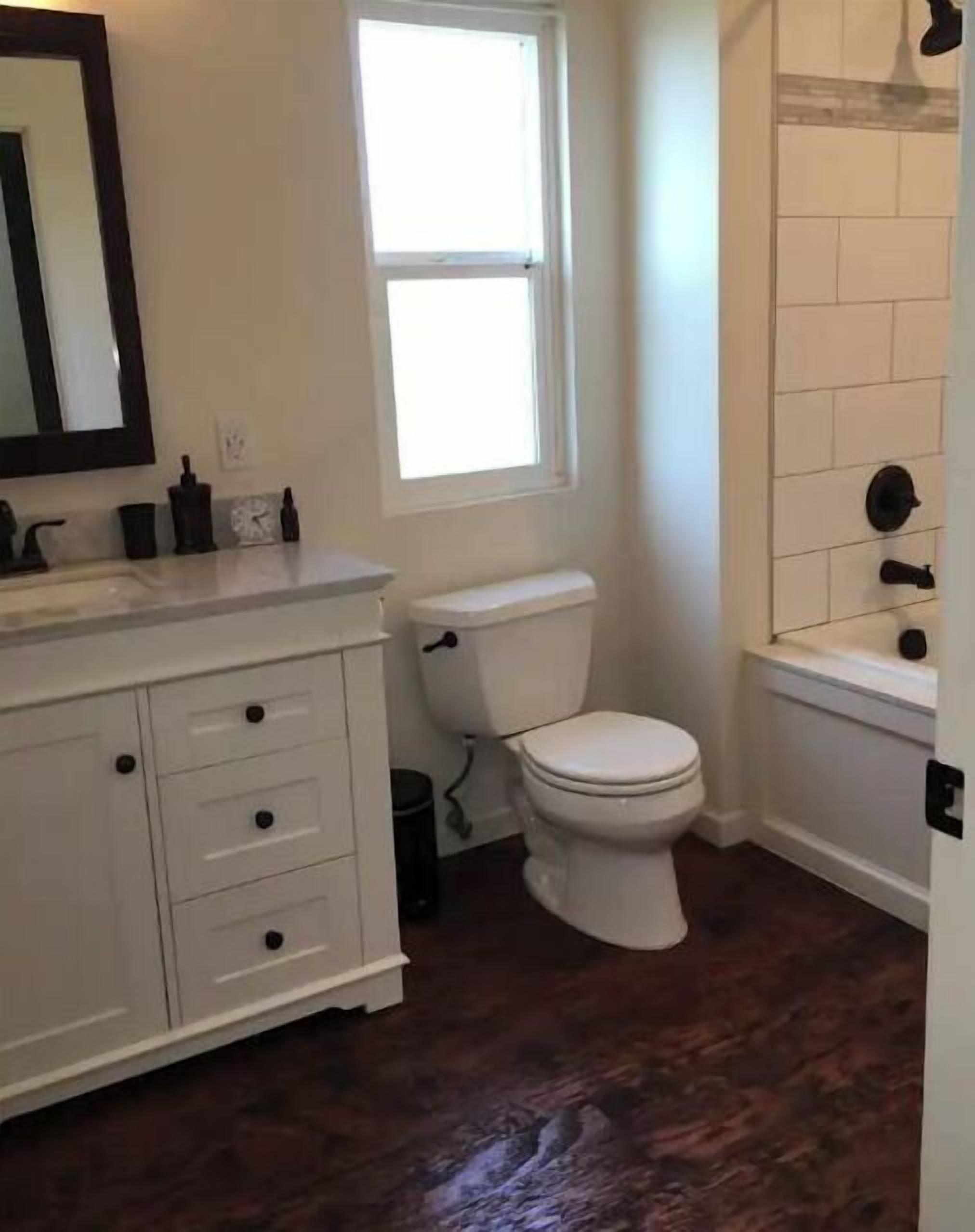 Een badkamer met een wit toilet, een wastafel met spiegel en een raam.
