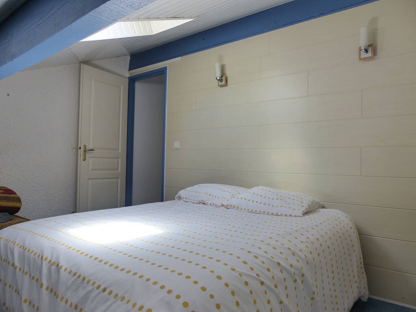 Een slaapkamer met een bed, een deur en een lamp aan de muur.