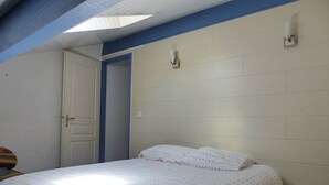 Um quarto com cama, uma porta e luminária na parede.