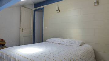 Een slaapkamer met een bed, een deur en een lamp aan de muur.