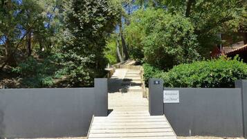 Un sentier en bois mène à un bâtiment portant l’inscription « Résidence Les Dunes ».