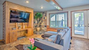 Ein Wohnzimmer mit Fernseher, einer Holz-Unterhaltungseinheit, einer Steinwand und einem Sofa.