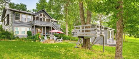 A two-story house with a balcony, surrounded by a well-maintained lawn and tall trees.