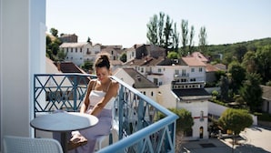 Ein Balkon mit Tisch und Stühlen, mit Blick auf ein Wohngebiet mit Häusern und Bäumen.