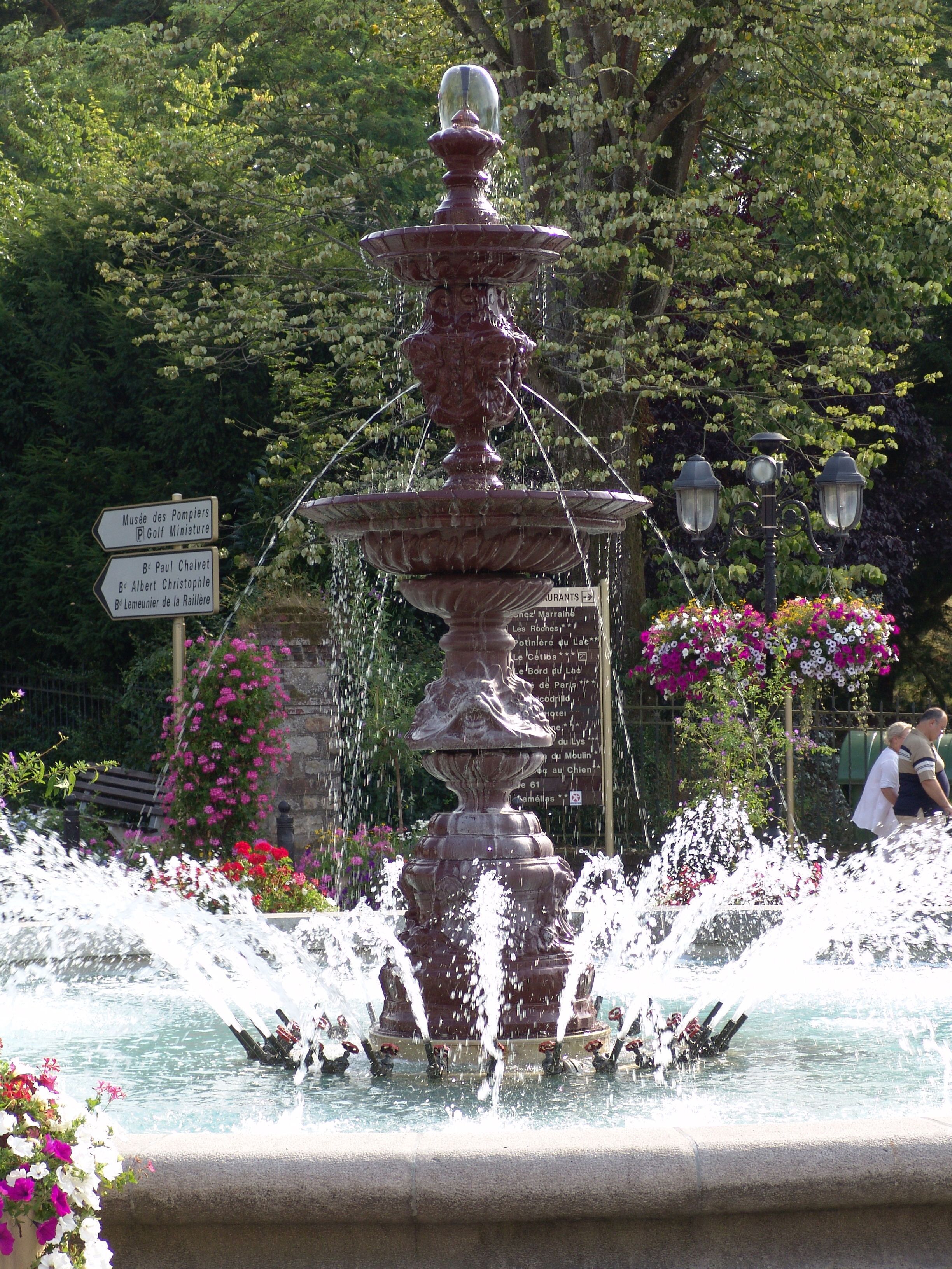 A multi-tiered fountain with water jets in a garden setting.