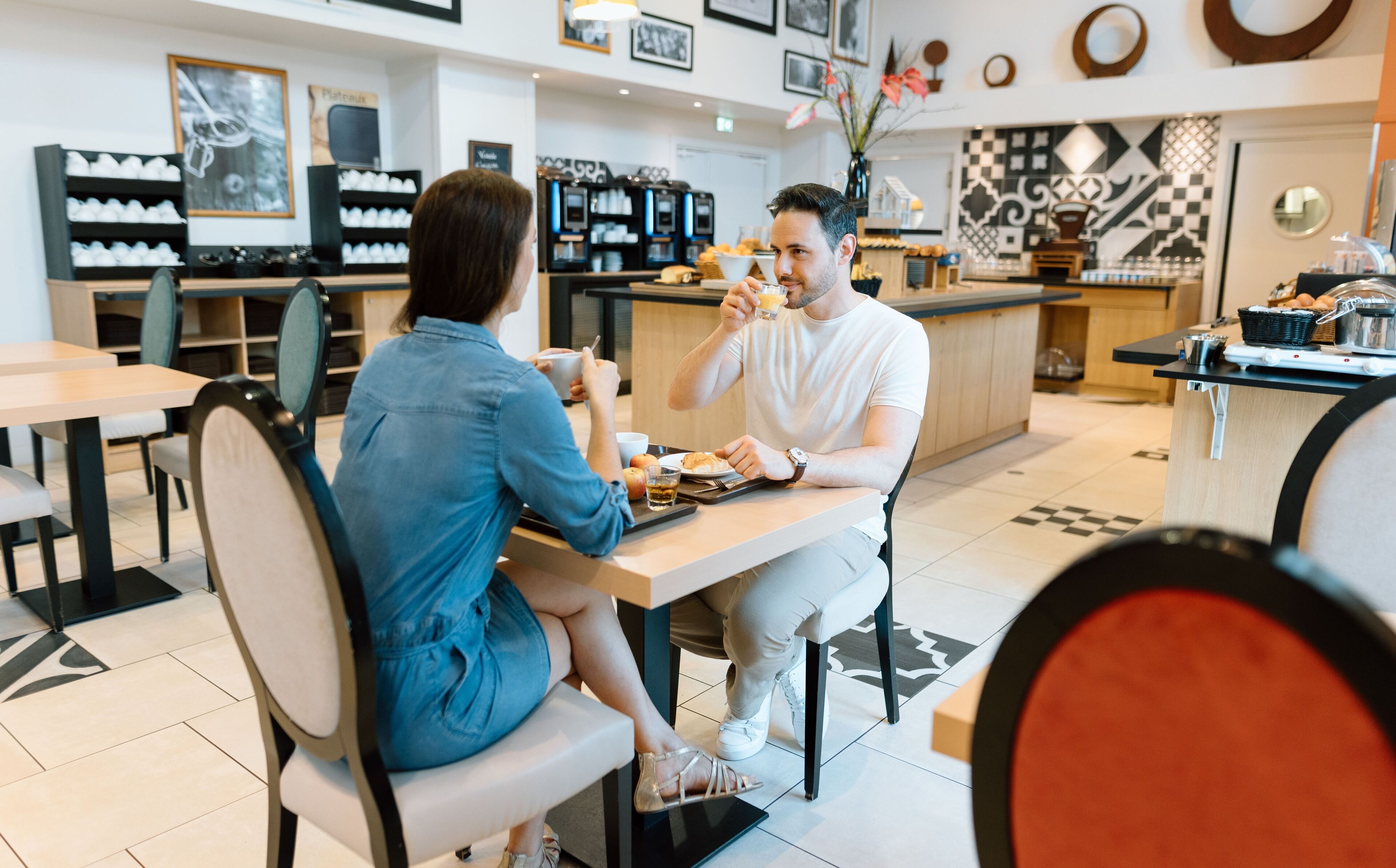 A cafe with a modern interior, including a coffee machine, seating area, and a counter with pastries.