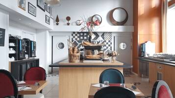 Un café moderne avec un comptoir central en bois, des chaises rouges et bleues, et une machine à café.