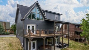 A two-story house with a balcony, a deck, and a patio area.