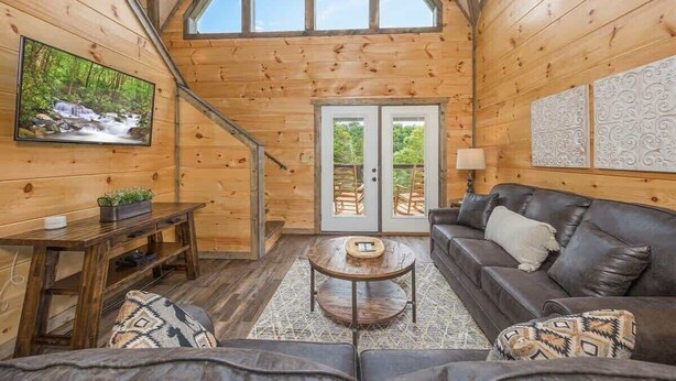 A cozy cabin interior with a wooden interior, a fireplace, a sofa, and a television.