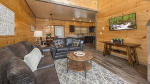 A cozy log cabin interior with a living room, kitchen, and dining area.