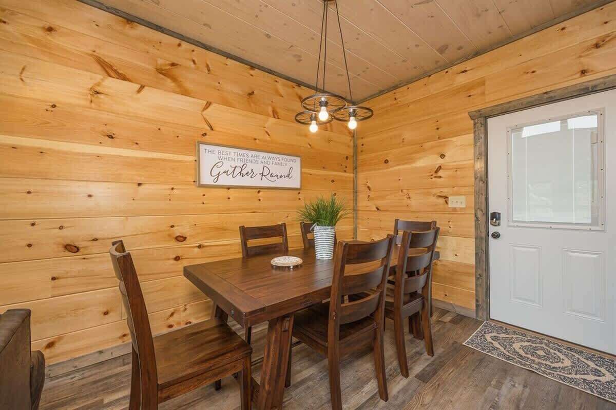 Un interno in legno con un tavolo da pranzo, sedie, una pianta in vaso e un cartello appeso al muro.